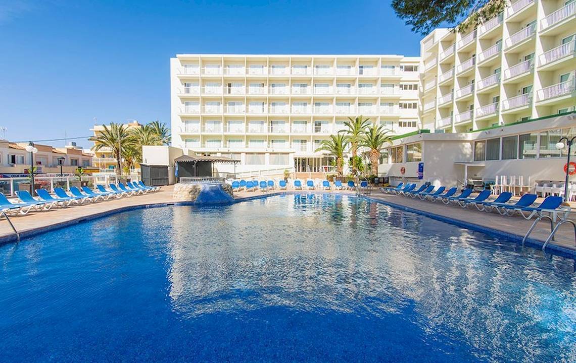 Blick auf den Pool des Hotels Moon Dreams Coral Beach mit Liegen und Palmen im Hintergrund.