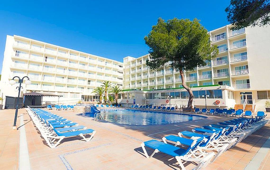 Außenansicht des Hotels Moon Dreams Coral Beach mit Pool und Liegen unter strahlend blauem Himmel.