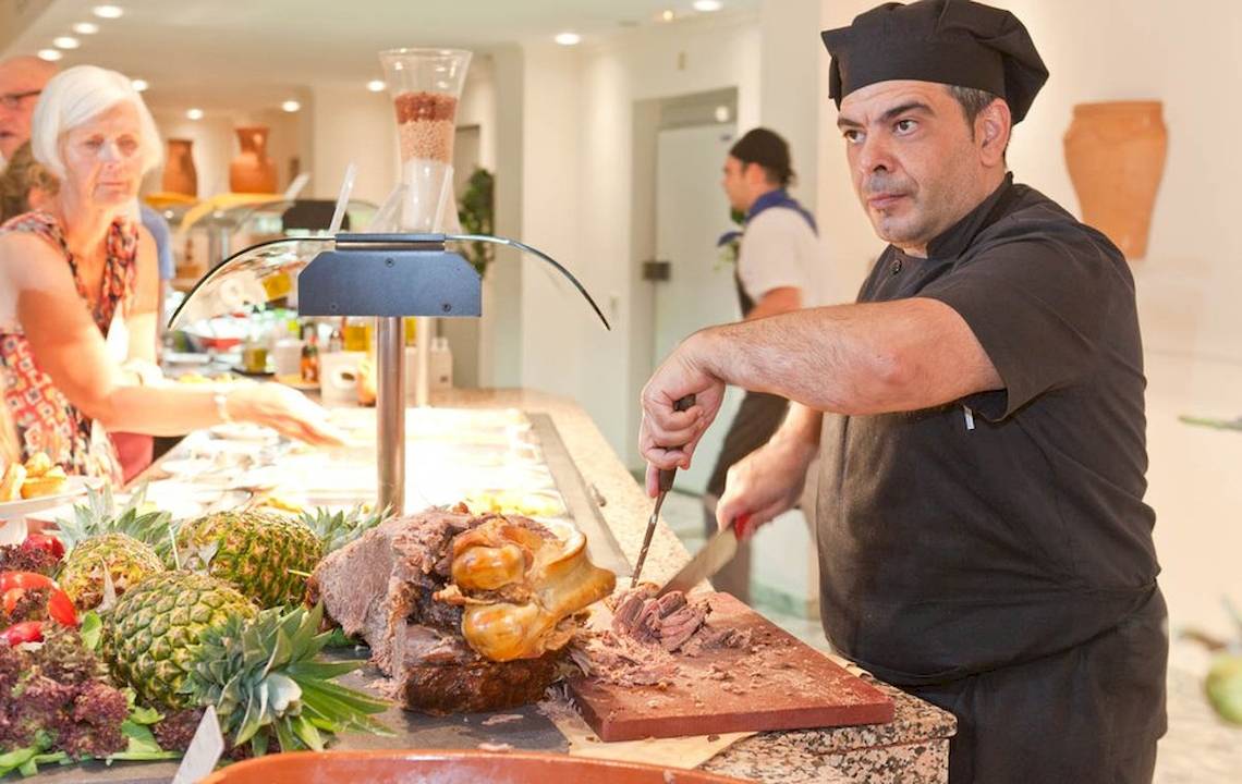 Ein Koch schneidet Fleisch an einem Buffet im Moon Dreams Coral Beach, umgeben von frischen Zutaten.