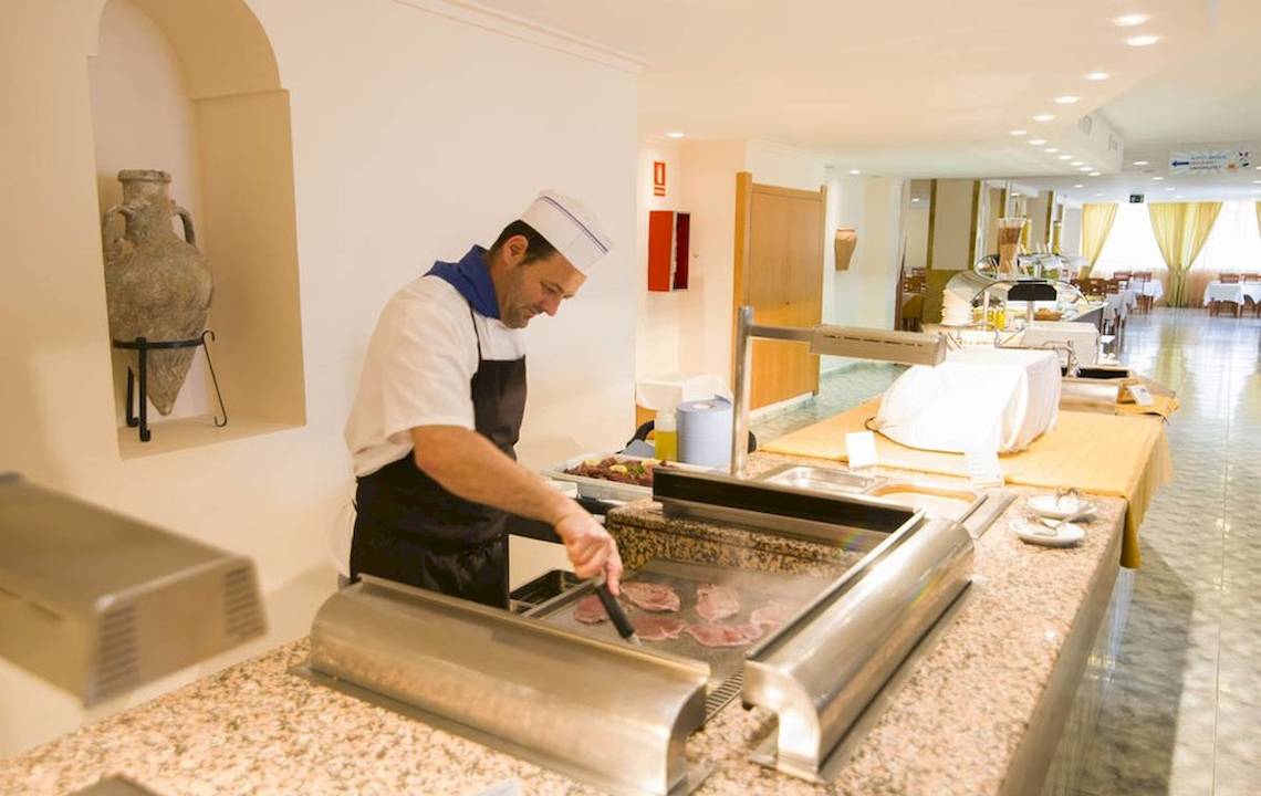 Ein Koch bereitet Fleisch im Restaurant des Moon Dreams Coral Beach Hotels zu.