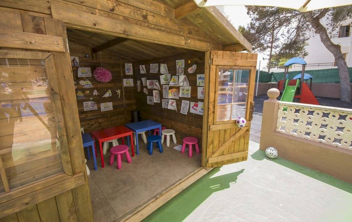 Ein Spielzimmer im Hotel Moon Dreams Coral Beach mit bunten Tischen, Stühlen und Kinderzeichnungen an der Wand.