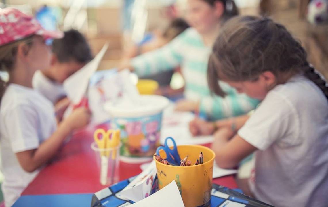 Kinder basteln bei Moon Dreams Coral Beach an einem Tisch mit bunten Malutensilien und Papier.