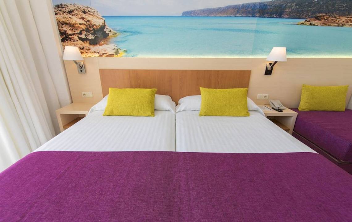 Doppelzimmer im Hotel Moon Dreams Coral Beach mit bunten Kissen und Meerblick-Wanddekoration.