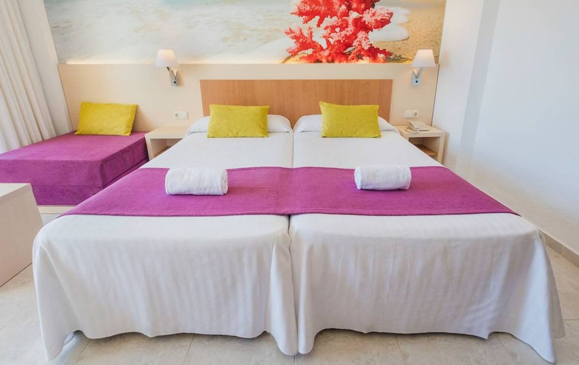 Zwei Betten in einem hellen Zimmer mit bunten Kissen im Hotel Moon Dreams Coral Beach.