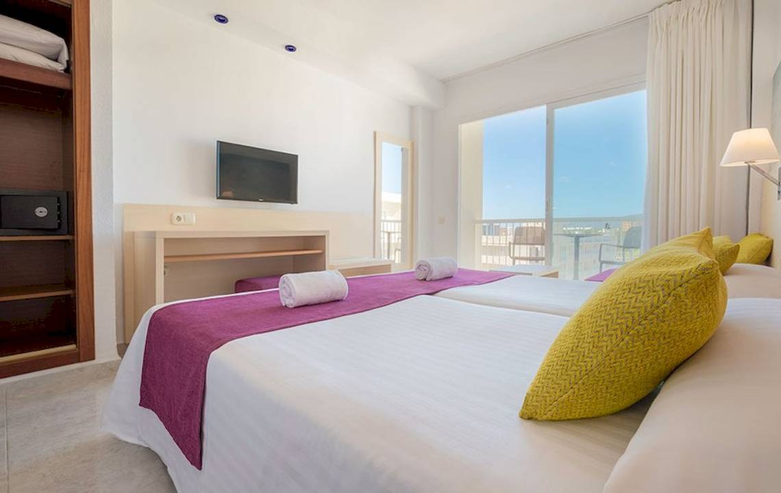 Helles Hotelzimmer im Moon Dreams Coral Beach mit zwei Betten, Fernseher und Fenster mit Meerblick.