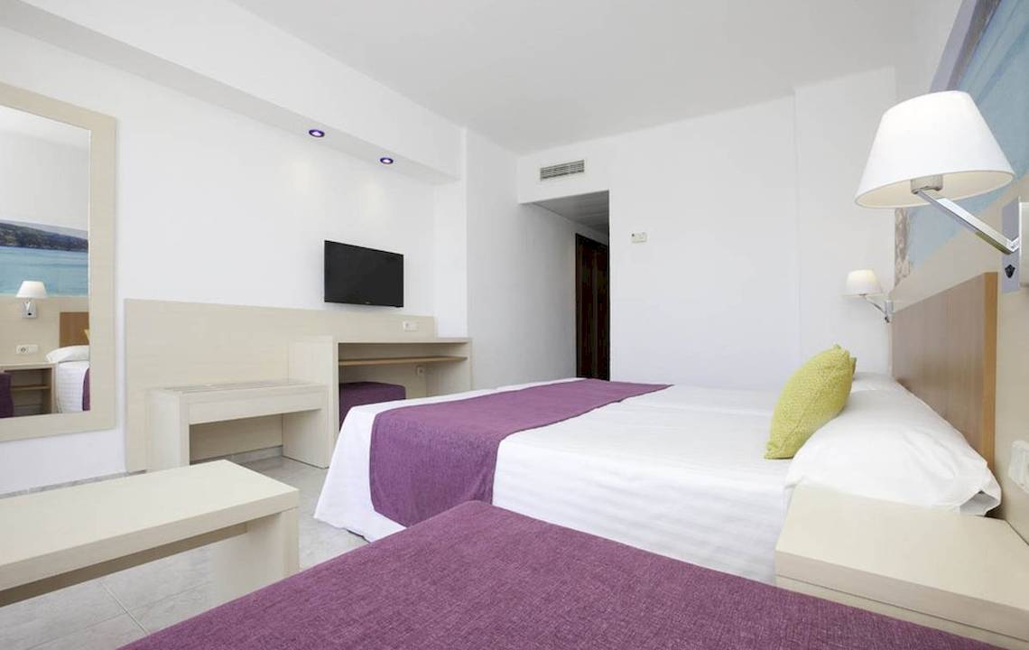Zimmer im Hotel Moon Dreams Coral Beach mit Doppelbett, TV und modernem, hellem Design.