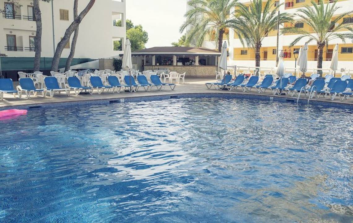 Ein Schwimmbecken mit blauen Liegen und Palmen, Hotel Moon Dreams Coral Beach im Hintergrund.
