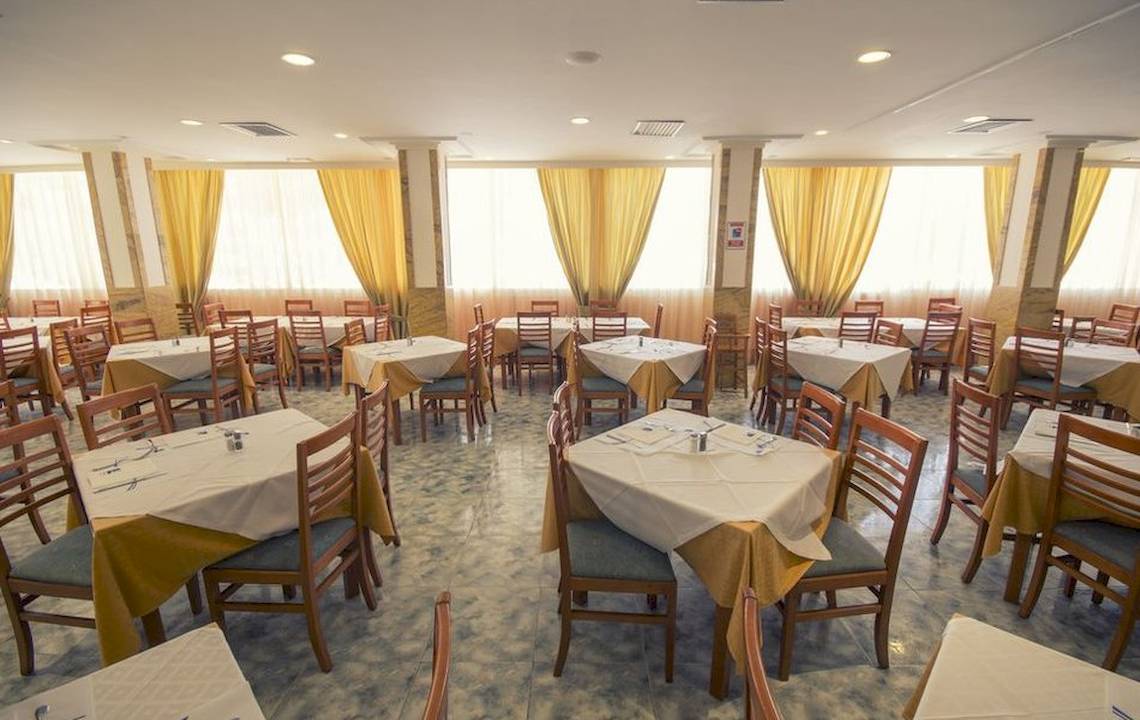 Elegantes Restaurant im Hotel Moon Dreams Coral Beach mit Tischen und stimmungsvollem Licht durch Vorhänge.