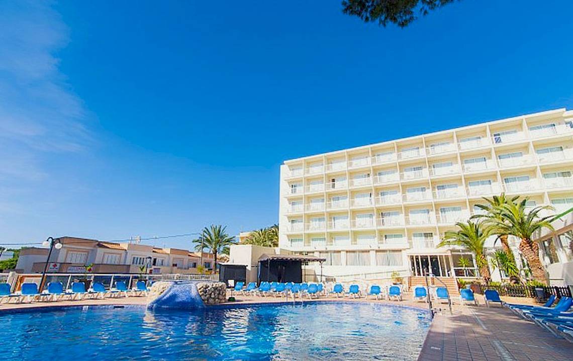 Hotel Moon Dreams Coral Beach mit Pool und Liegen unter blauem Himmel und Palmen im Hintergrund.