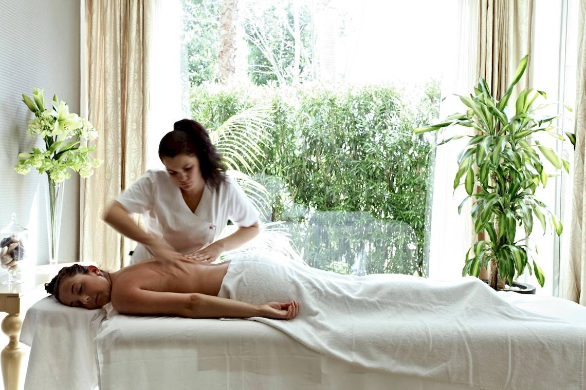 Eine Frau im weißen Kleid führt eine Massage an einem Mann im Zafiro Tropic Hotel durch.