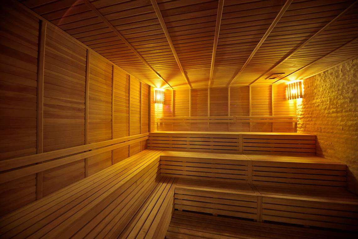 Innenansicht der Sauna im White City Resort mit hölzernen Wänden und Bänken sowie warmem Licht.