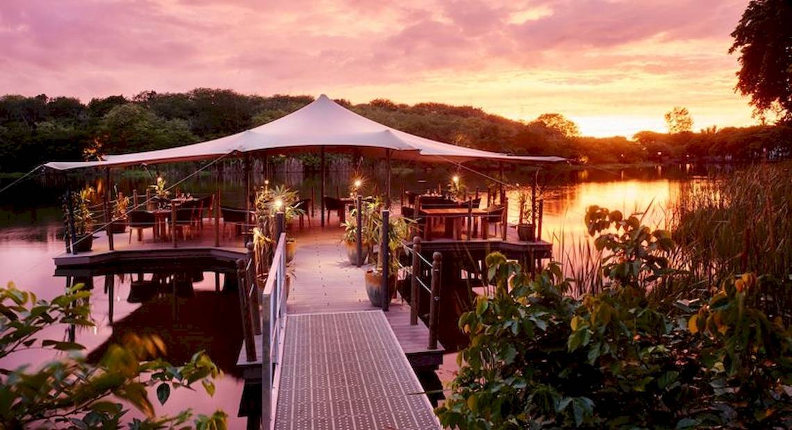 Das Hotel 'The Ravenala Attitude' mit einer Terrasse am See bei Sonnenuntergang.