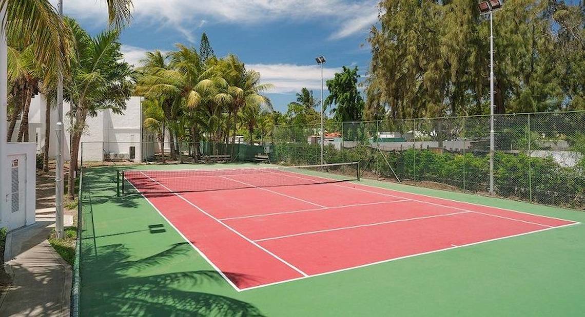 Tennisplatz im Freien im Hotel The Ravenala Attitude mit rotem Boden und grünem Rand.