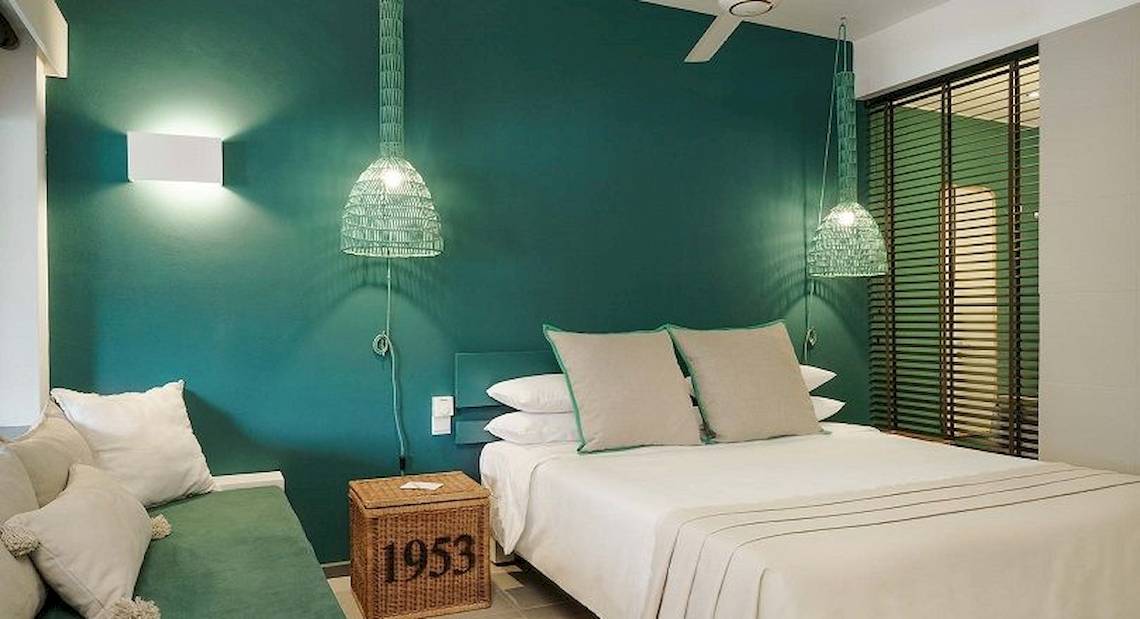 Schlafzimmer im The Ravenala Attitude Hotel mit grünen Wänden, zwei Betten und Lampen