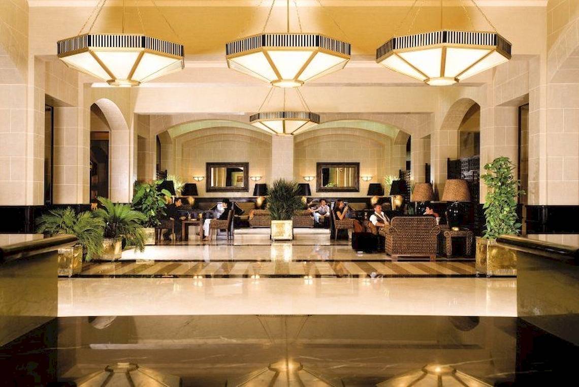 Lobby des Jaz Solaya Hotels mit gemusterten Kronleuchtern und Gästen, die sich entspannen.