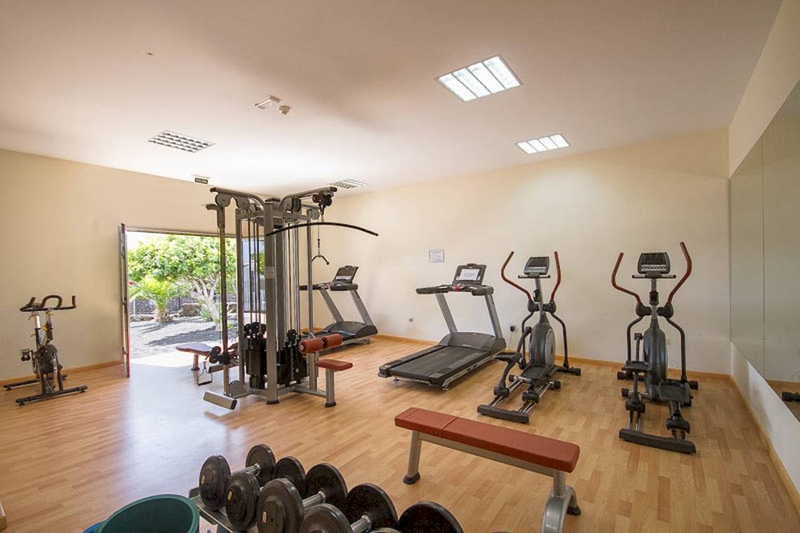 Fitnessbereich im Lanzarote Village Hotel mit diversen Trainingsgeräten und einer offenen Tür zum Freien.
