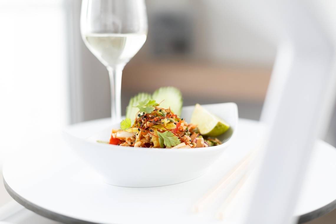 Schale mit thailändischem Salat und einem Glas Weißwein
