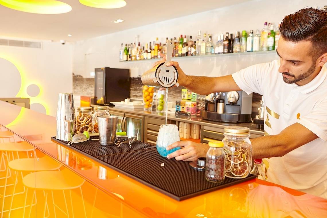 Ein Barkeeper in der Hotelbar der Ibiza Sun Apartments mischt einen Cocktail.