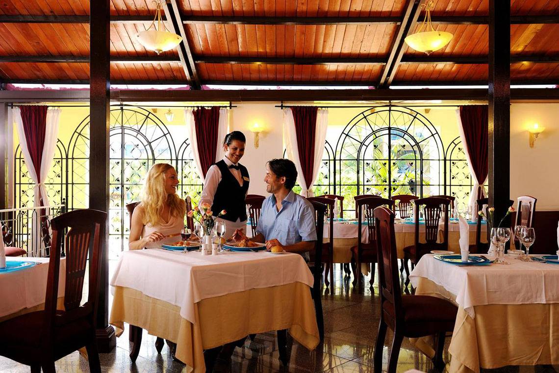 Im Iberostar Playa Alameda Restaurant sitzen ein Paar an einem Tisch und essen mit einem Kellner.