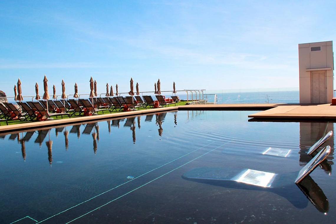 Poolterrasse des Riviera Vista Hotels mit Sonnenliegen und Schirmen am Meer
