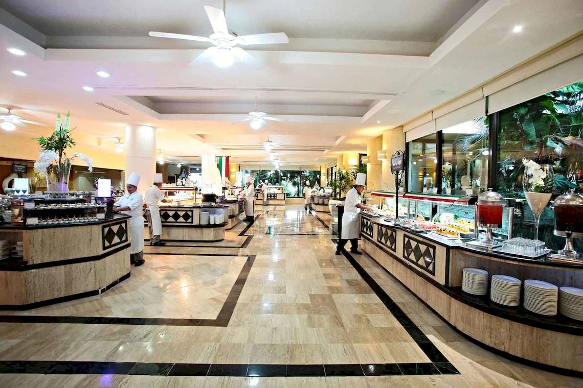 Restaurant im Hotel Bahia Principe Luxury Akumal mit mehreren Köchen und Speisen auf den Tischen.