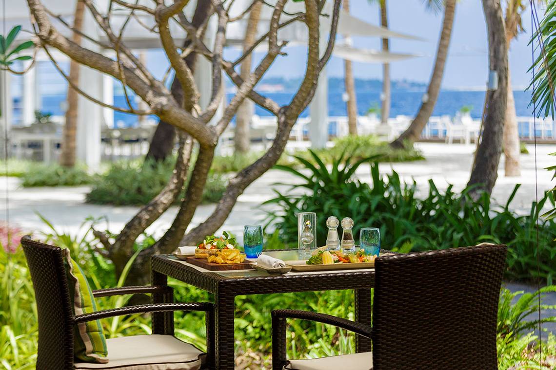 Außenbereich des Kurumba Maldives Hotels mit einem Tisch, auf dem Essen serviert wird.