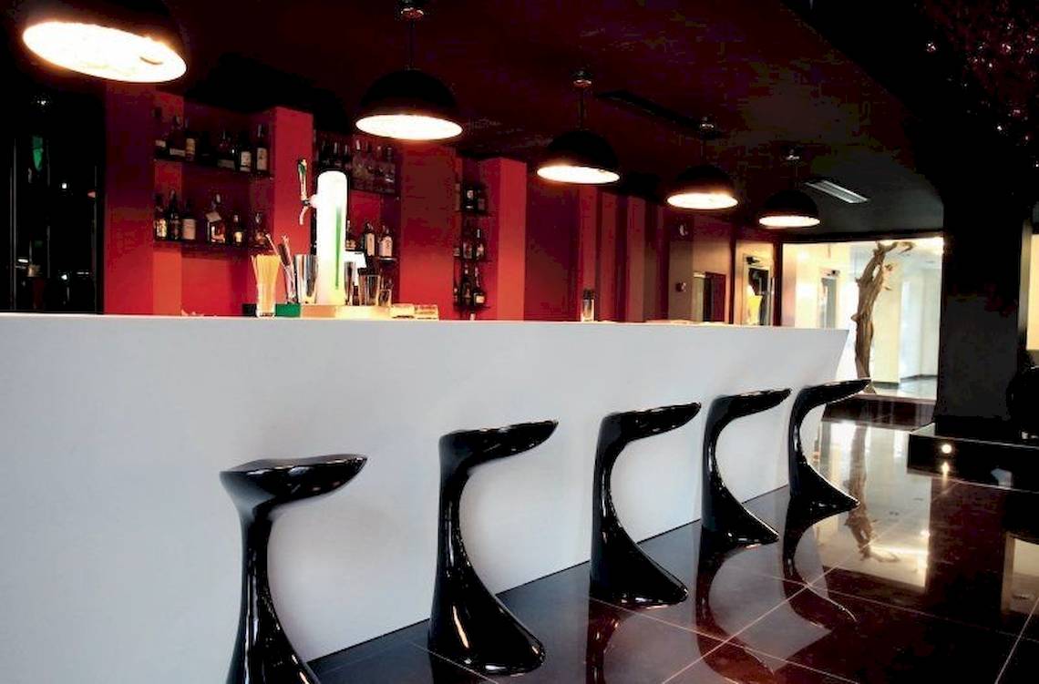 Barbereich im Ushuaia Ibiza Beach Hotel mit schwarzen Stühlen und roten Wänden.