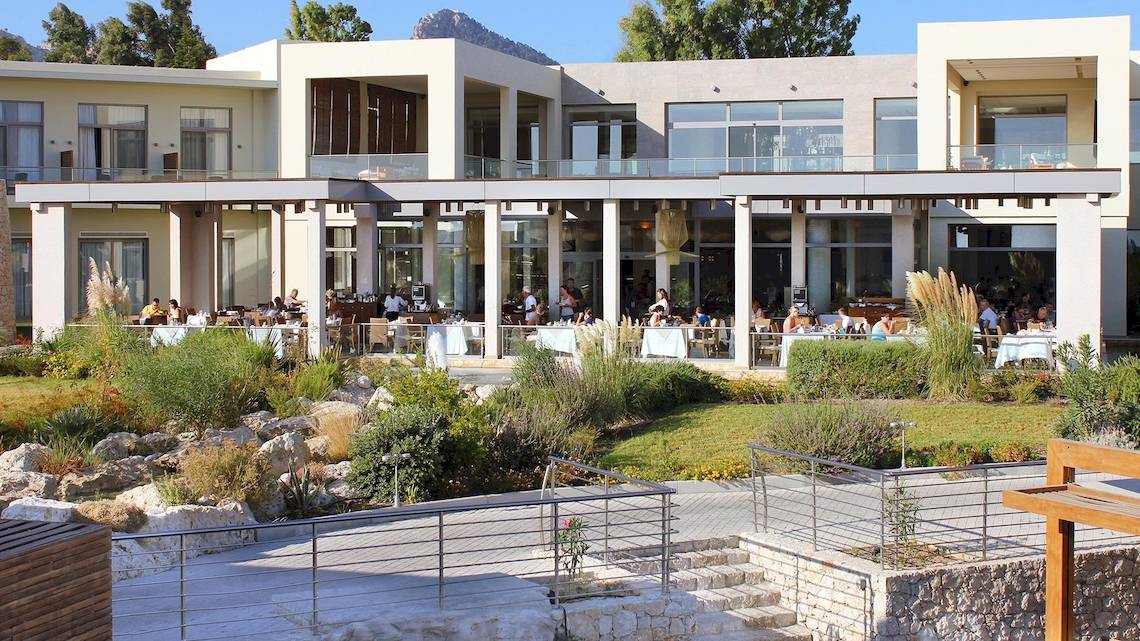 Außenbereich des Sentido Port Royal Villas & Spa Hotels mit Gästen, die drinnen und draußen essen