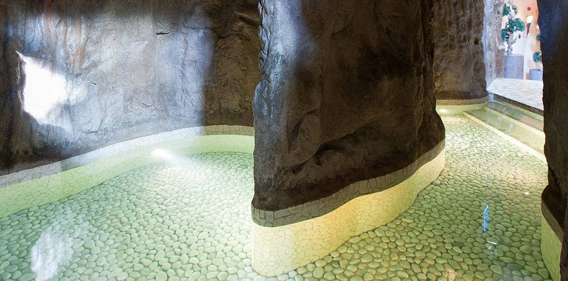 Ein Becken mit grünen Steinen und einem großen Felsen, der als Teil einer Hoteleinrichtung dient.