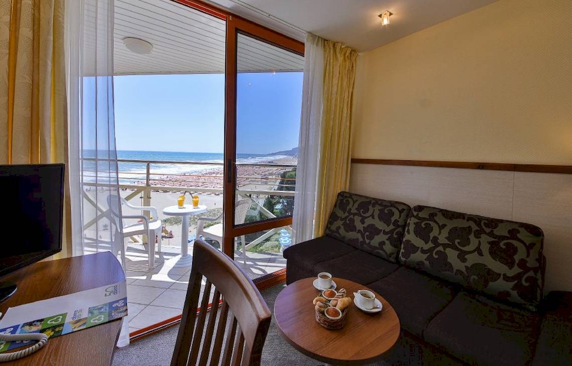 Hotelzimmer mit Meerblick im Kaliakra Beach Hotel, mit Sofa, Tisch, Fernseher und Balkon.