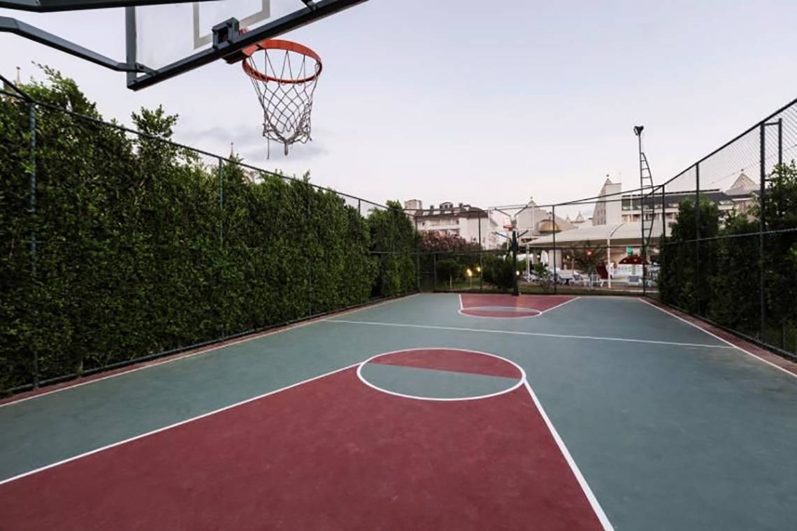 Basketballplatz im Calimera Hane Garden Hotel mit umzäunten Bereich und Gebäude im Hintergrund.