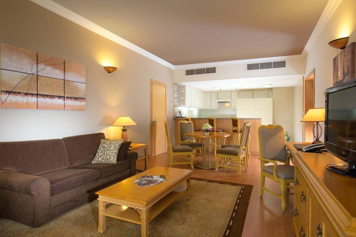 Wohnbereich des Millennium Plaza Downtown Hotels mit Sofa, Couchtisch, Fernseher und Esstisch.