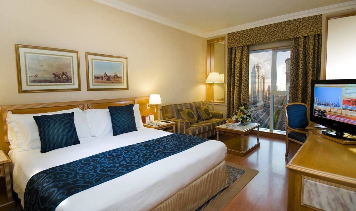 Hotelzimmer im Millennium Plaza Downtown mit Bett, Sofa, Fernseher und Stadtblick.