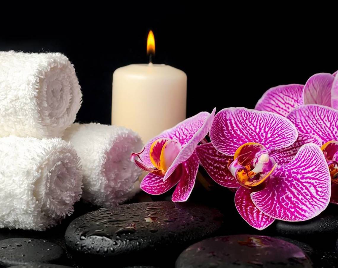 Spa-Einrichtung mit Kerze, Orchideen, Handtüchern und Steinen im Millennium Plaza Downtown Hotel