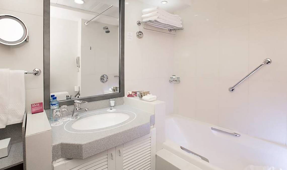 Badezimmer im Millennium Plaza Downtown Hotel mit Badewanne, Waschbecken und Spiegel