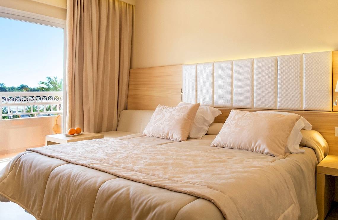 Schlafzimmer im VIVA Blue & Spa Hotel mit Blick auf den Balkon und die Palmen draußen