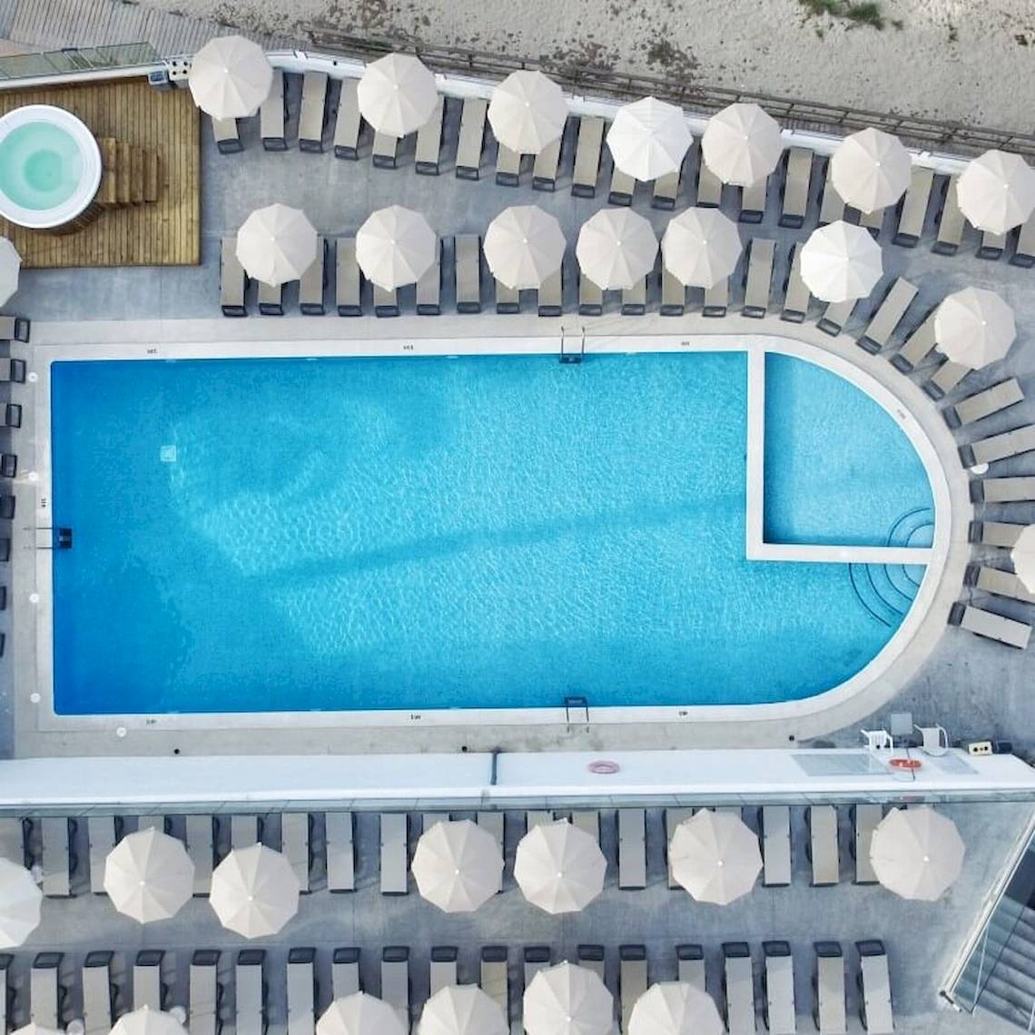 Luftaufnahme des Sandos El Greco Beach Pools mit Sonnenliegen und Sonnenschirmen