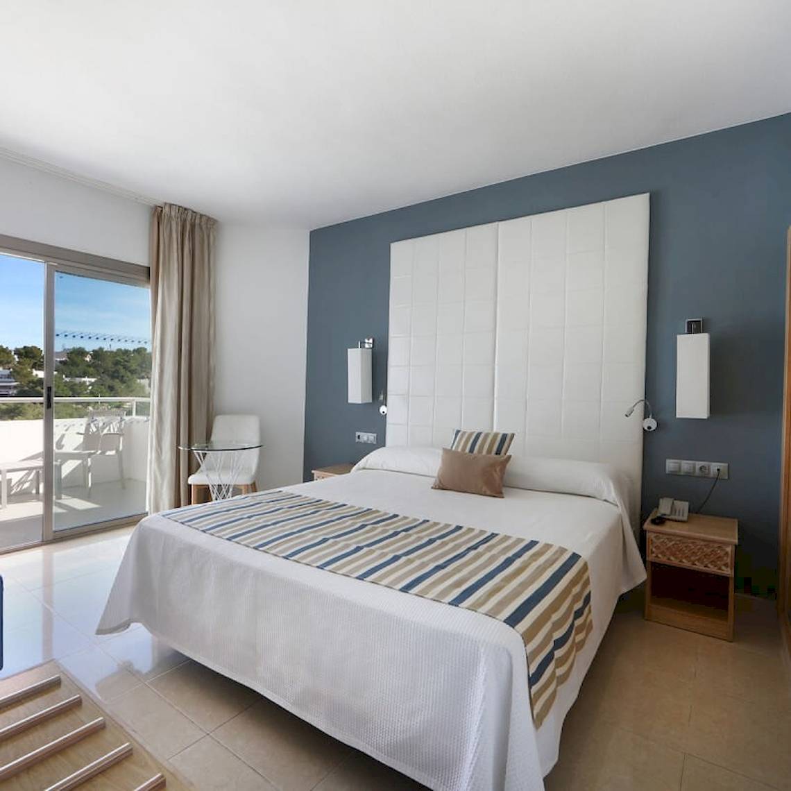 Schlafzimmer im Sandos El Greco Beach Hotel mit Bett, Balkon und modernen Möbeln.