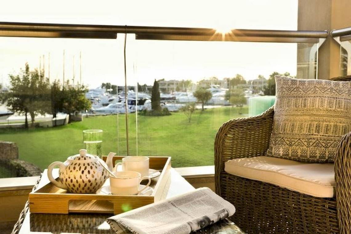 Aussicht von der Terrasse des Porto Sani Hotels mit einem Tisch, Tassen und Zeitung.