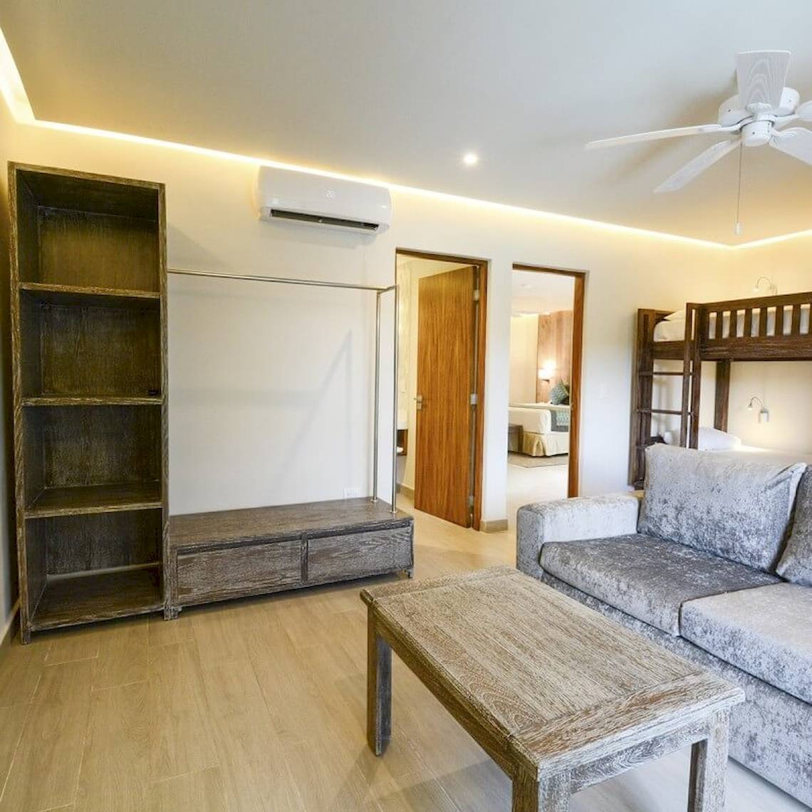 Wohnzimmer im Sandos Caracol Eco Resort mit Sofa, Couchtisch, Bücherregal und Klimaanlage.