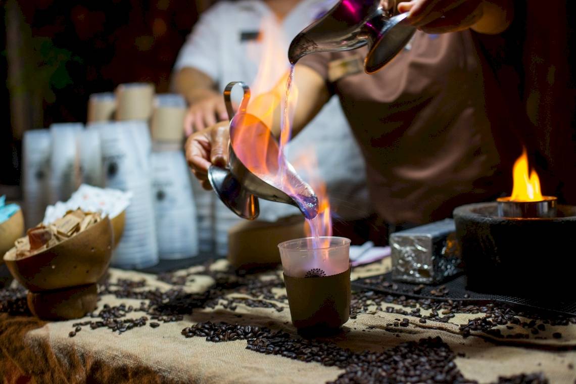 Ein Mitarbeiter des Sandos Caracol Eco Resorts führt eine Feuershow mit Kaffee durch.