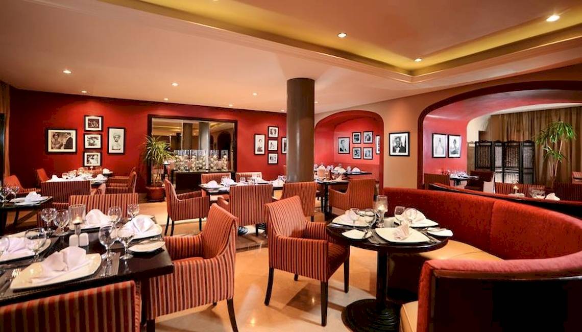 Innenbereich eines Restaurants im Jaz Aquamarine Resort mit roten Wänden, Tischdecken und Fotos an der Wand.