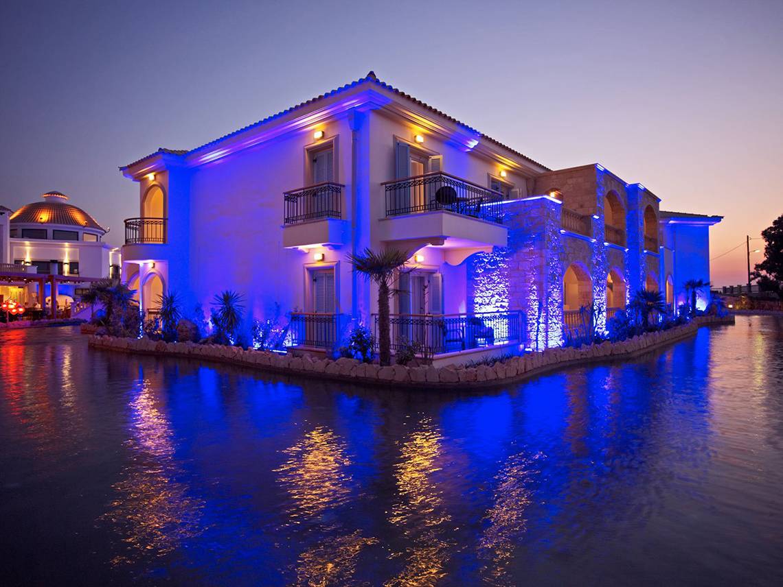 Mitsis Laguna Resort bei Nacht mit blauen Beleuchtung und Wasserreflexion