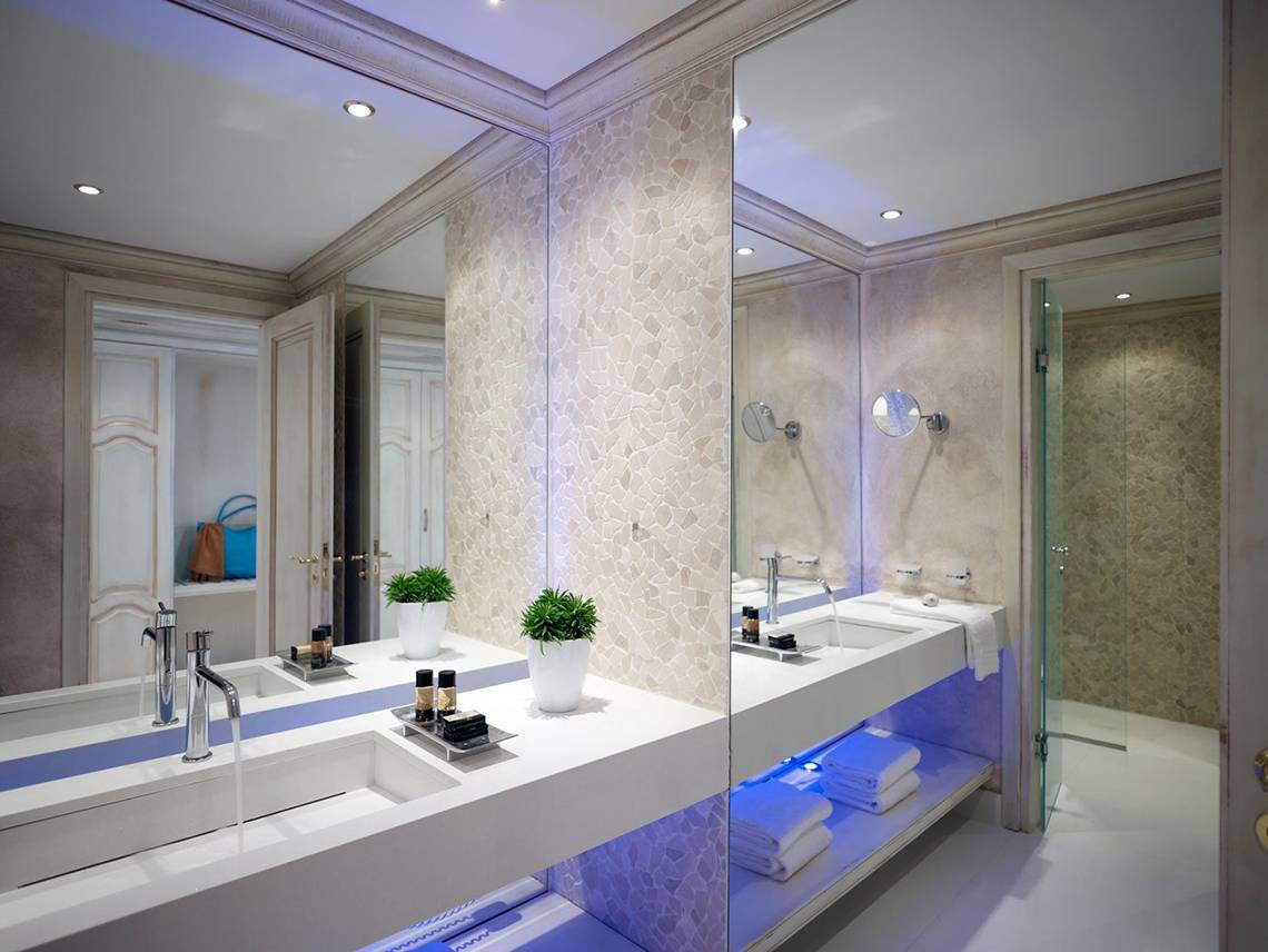 Badezimmer im Mitsis Laguna Resort mit zwei Waschbecken, Spiegeln und einer Glasdusche.