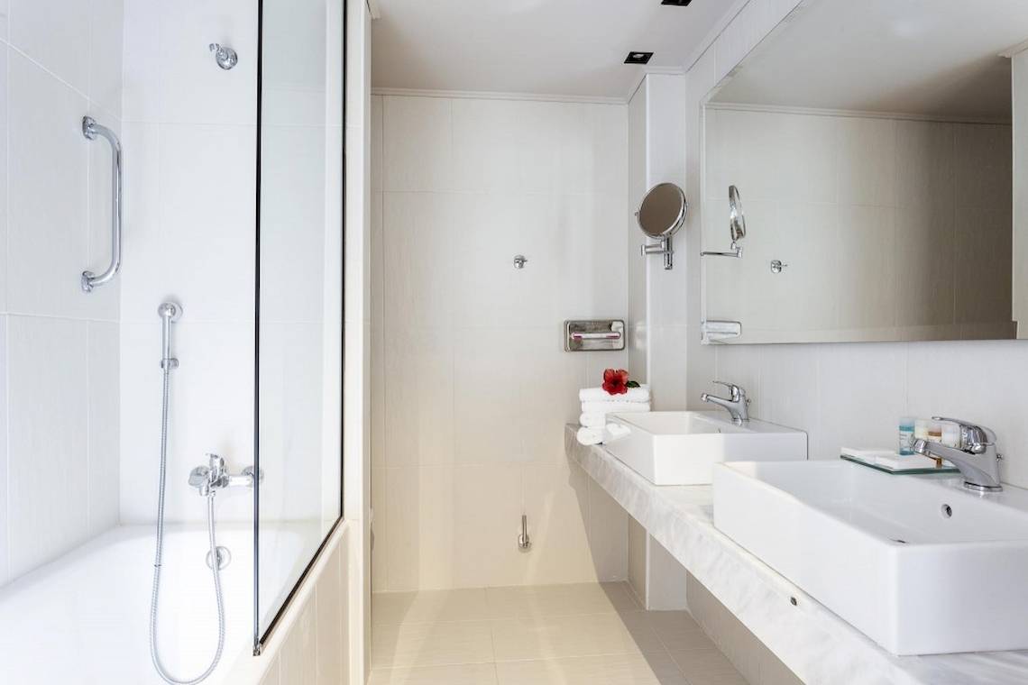 Ein modernes Badezimmer mit zwei Waschbecken, einer Dusche und einem Spiegel im Aeolos Beach Resort auf Korfu.