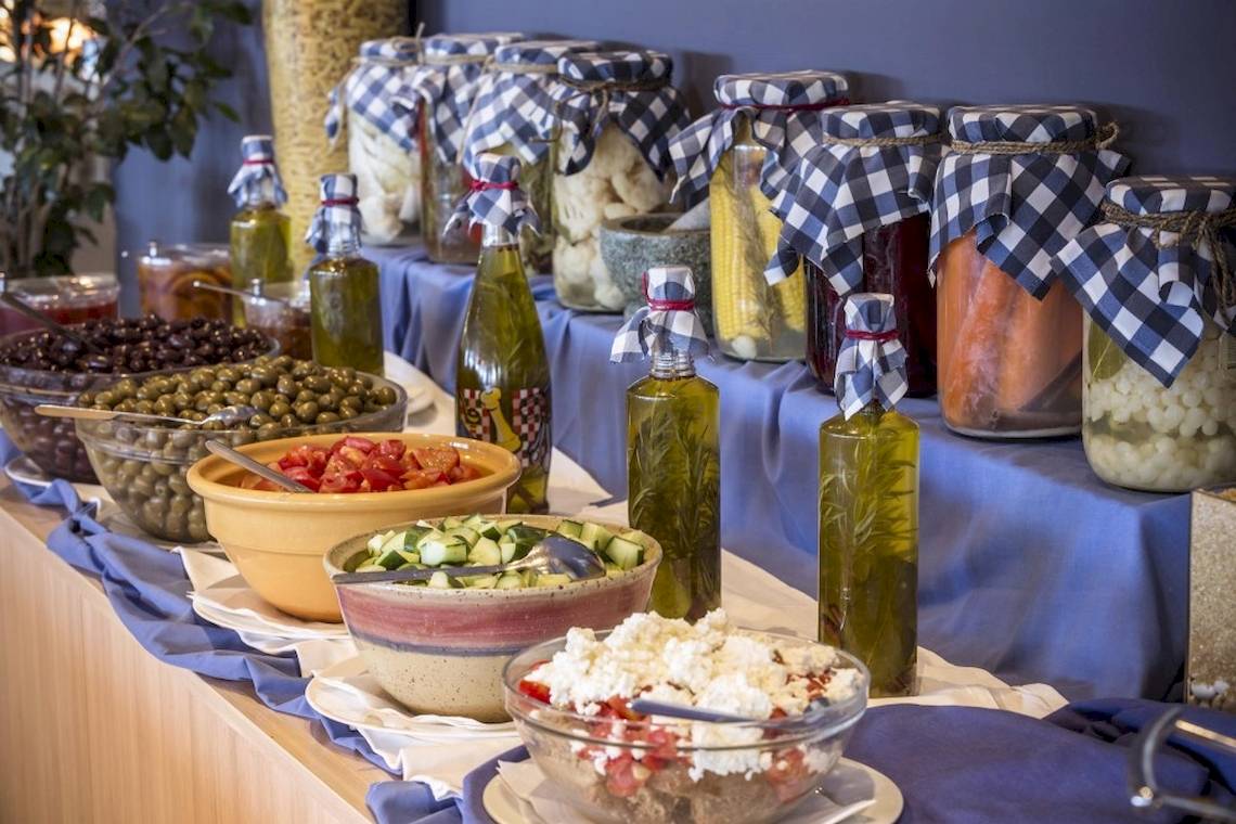 Buffettisch im Aeolos Beach Resort auf Korfu mit verschiedenen Salatschüsseln, Oliven, Ölflaschen und eingemachten Gemüse.
