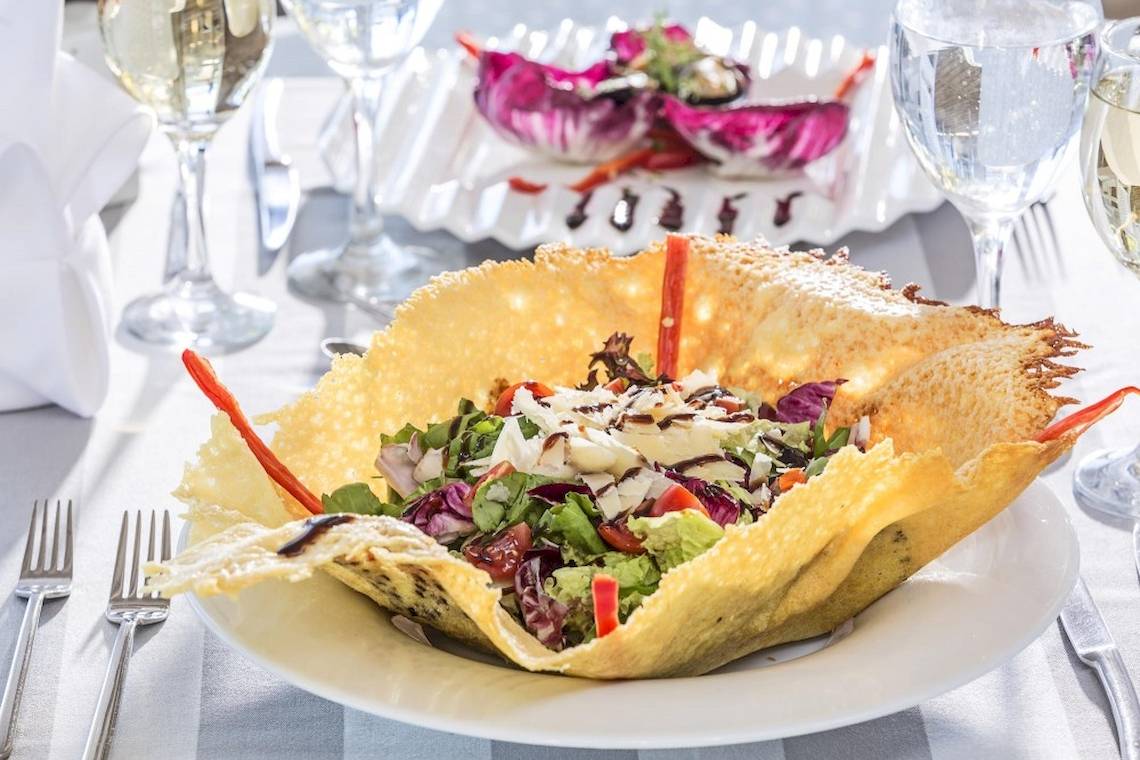 Salat im Kornchip-Schälchen auf einem Tisch serviert mit Gläsern und Besteck.