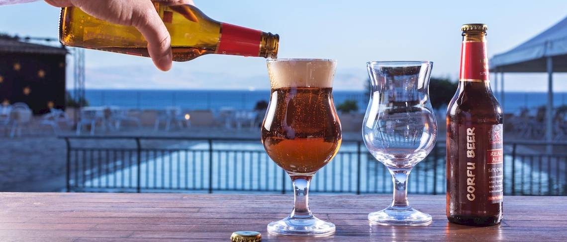 Hand gießt Bier in ein Glas im Aeolos Beach Resort auf Korfu