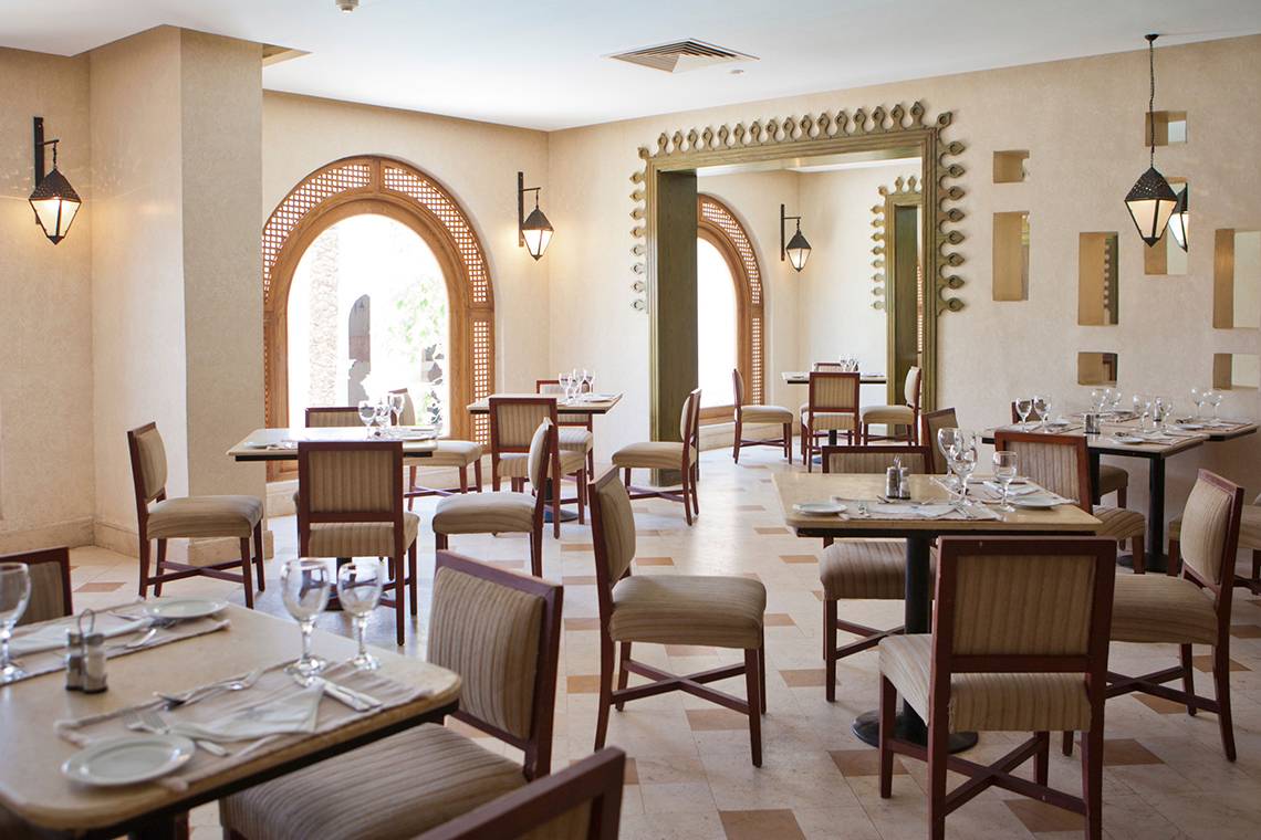 Innenbereich des Ghazala Gardens Restaurants mit runden Bögen, Tischen und Stühlen.