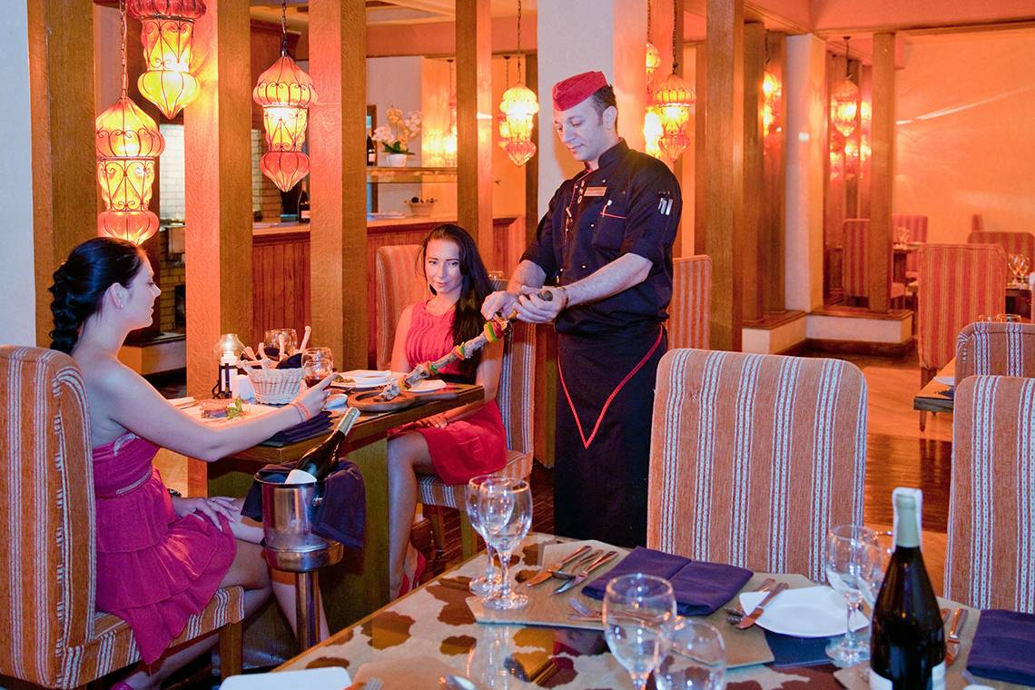 Im Ghazala Gardens Hotel sitzen zwei Frauen am Tisch, während ein Kellner ihnen serviert.
